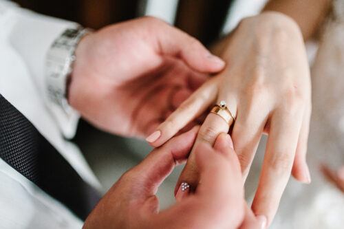 The hands of the groom wears a wedding engagement ring on the finger of the bride. Preparations. Wedding ceremony. Jewelry. close up.